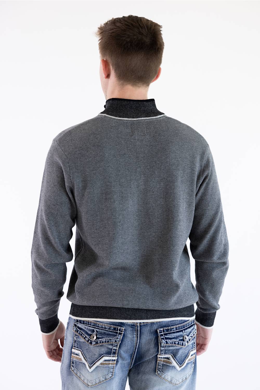 A back view of a male model wearing the F/X Fusion Birdseye Knit Quarter Zip in nickel gray, showing the textured knit back, dark contrasting collar trim, cuffs, and hem, paired with patterned-pocket denim jeans.