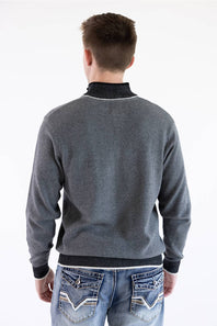 A back view of a male model wearing the F/X Fusion Birdseye Knit Quarter Zip in nickel gray, showing the textured knit back, dark contrasting collar trim, cuffs, and hem, paired with patterned-pocket denim jeans.