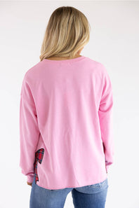 A woman viewed from behind wearing a light pink long-sleeve crewneck sweatshirt and blue jeans against a plain white background.