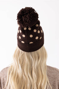 C.C. Polka Dot Pom Beanie for Women in Brown. A close-up view of the back of the knit hat, showing the brown main color, cream polka dots, dark brown fuzzy pom-pom, and ribbed cuffed hem.