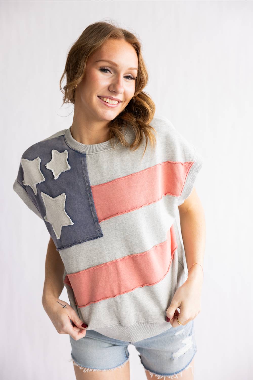 Woman wearing a sweater with an American flag design on a plain background