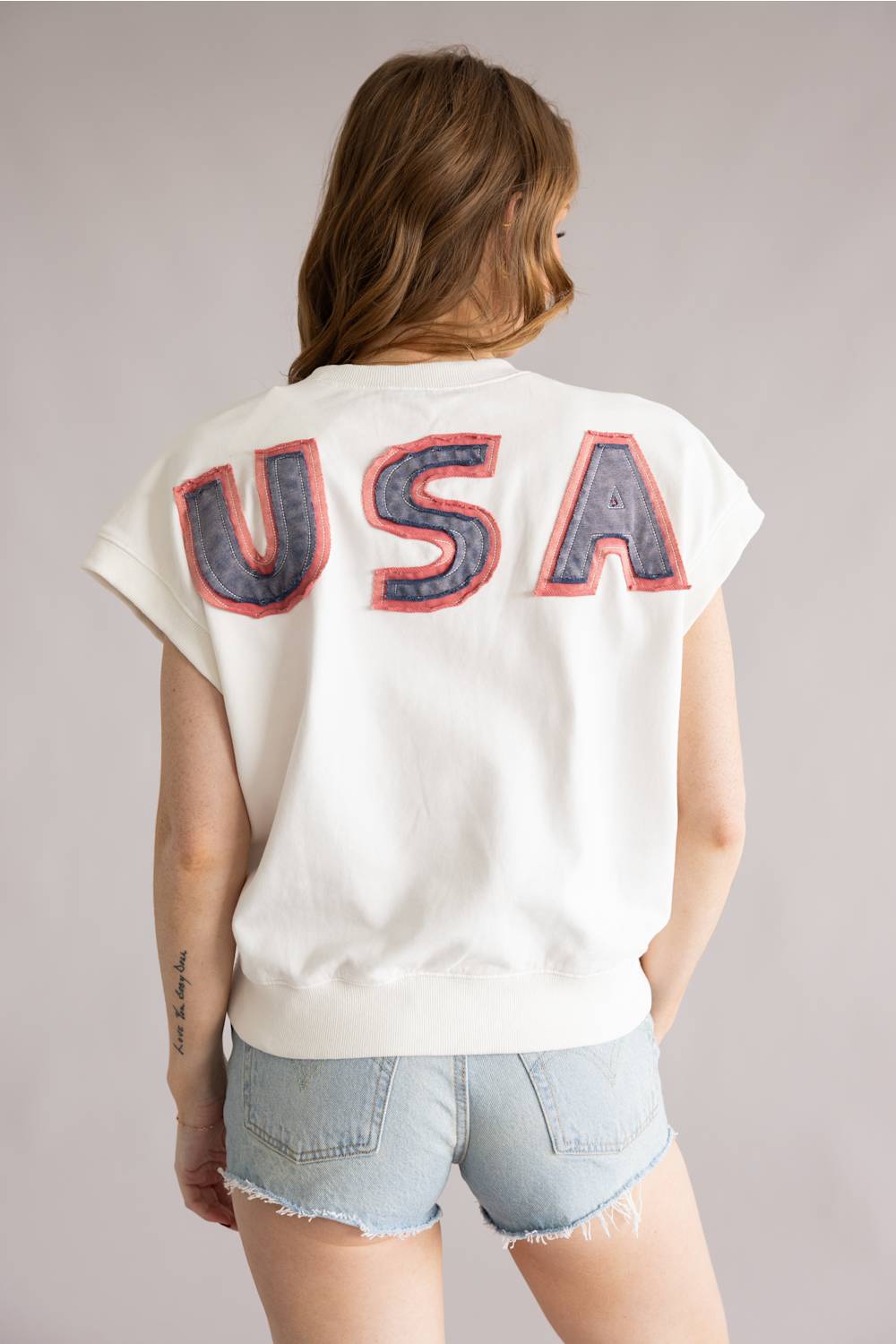Person wearing a white t-shirt with 'USA' printed on the back against a plain background