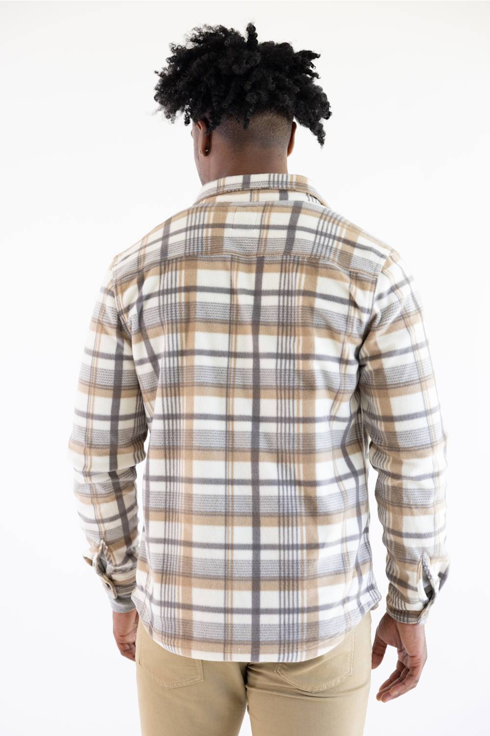 A man viewed from behind wearing a long-sleeve plaid button-up shirt in beige, white, and gray, paired with khaki pants, against a plain white background.