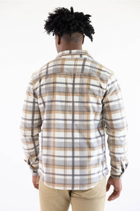A man viewed from behind wearing a long-sleeve plaid button-up shirt in beige, white, and gray, paired with khaki pants, against a plain white background.