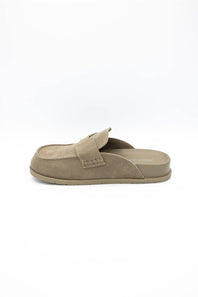 A single taupe-brown slip-on mule shoe with a suede-like upper and a small decorative strap detail on the side, shown from a side profile against a white background.