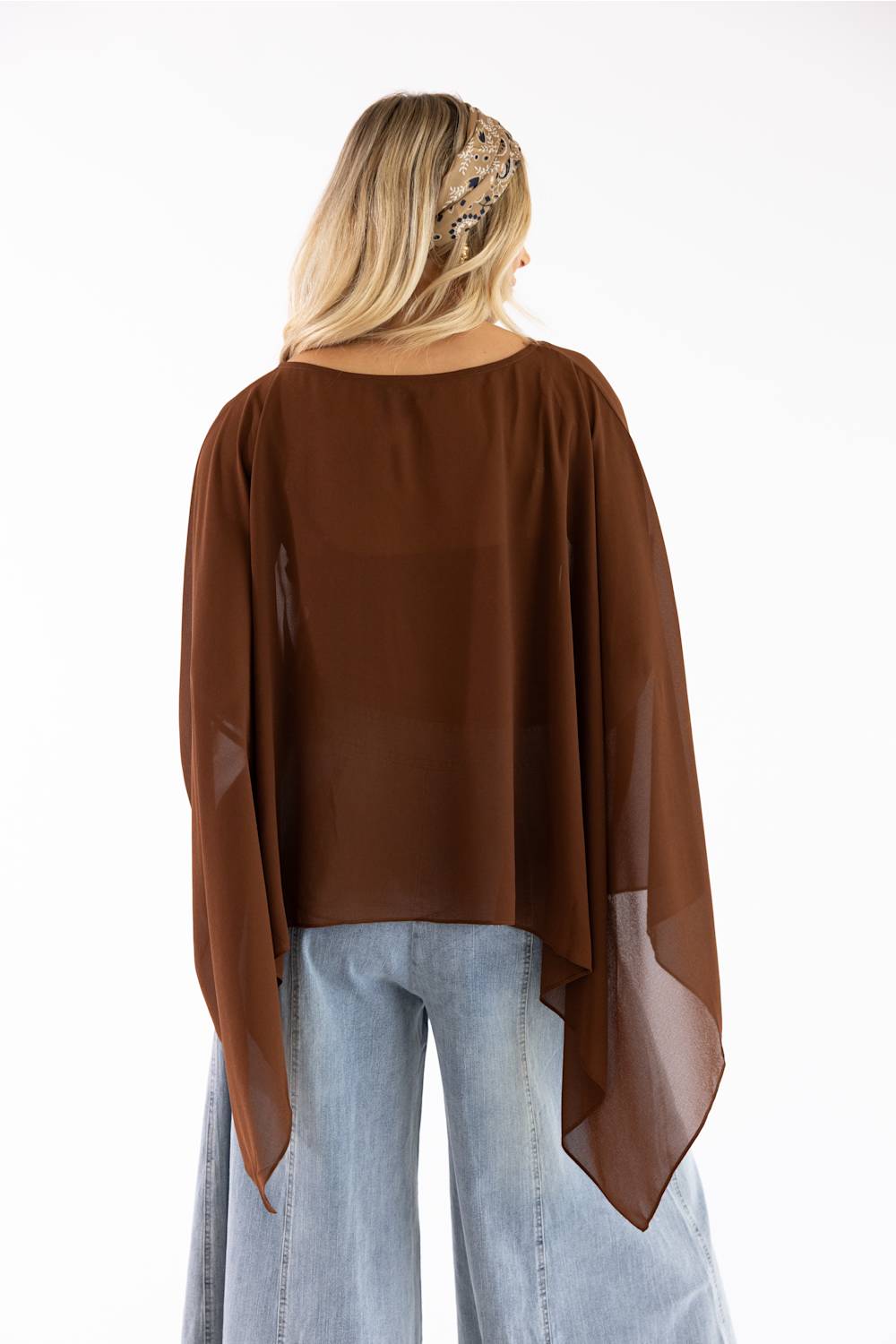 A woman viewed from the back wearing a brown sheer long-sleeve top with wide draped sleeves and light blue jeans, against a plain white background.