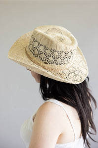 Person wearing a beige straw hat with a subtle pattern on a plain background