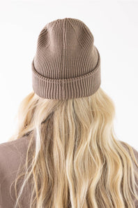 rear view showing the ribbed knit texture of the stone brown Carhartt watch cap beanie worn over blonde hair.