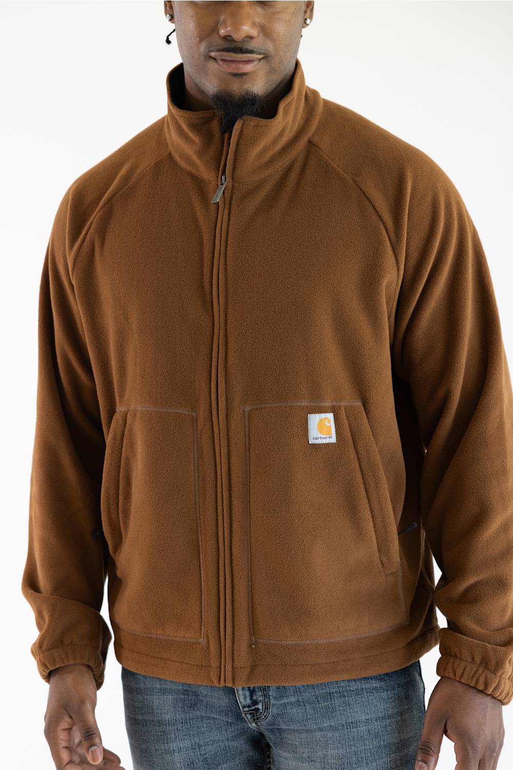 Cropped front view of a male model wearing the Carhartt Elkhart zip-up fleece jacket in Red Duck brown, showing the raglan shoulders, lower hand pockets, and the iconic square logo patch on the left pocket.