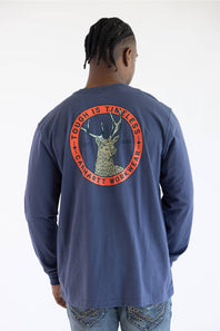 A man viewed from behind wearing a navy blue long-sleeve t-shirt with a large circular back graphic featuring a deer head and the text 'TOUGH IS TIMELESS' and 'CARHARTT WORKWEAR'.
