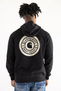 Back view of a man wearing a black Carhartt Sawyer fleece hoodie with a large circular emblem graphic featuring camo print, the Carhartt "C" logo, and "1889 Built To Last" lettering.