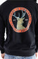 Back view of a man wearing a black Carhartt hooded sweatshirt featuring a large circular graphic on the back. The graphic displays a distressed orange border with the text "TOUGH IS TIMELESS" and "CARHARTT WORKWEAR," enclosing an illustration of a buck deer, the text "EST. 1889," and decorative stars.