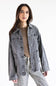 A woman modeling a washed gray denim jacket over a brown top and leopard-print pants against a plain white background.