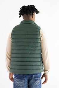 A man viewed from behind wearing a dark green quilted puffer vest over a beige long-sleeve shirt and blue jeans, against a plain white studio background.