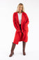 A woman modeling a bright red open-front knit cardigan over a white top and black pants, paired with brown knee-high boots, against a plain white studio background.