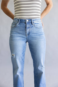 A person wearing light blue high-waisted straight-leg jeans with distressed details on the knees, paired with a black and white striped top, shown against a plain gray background.
