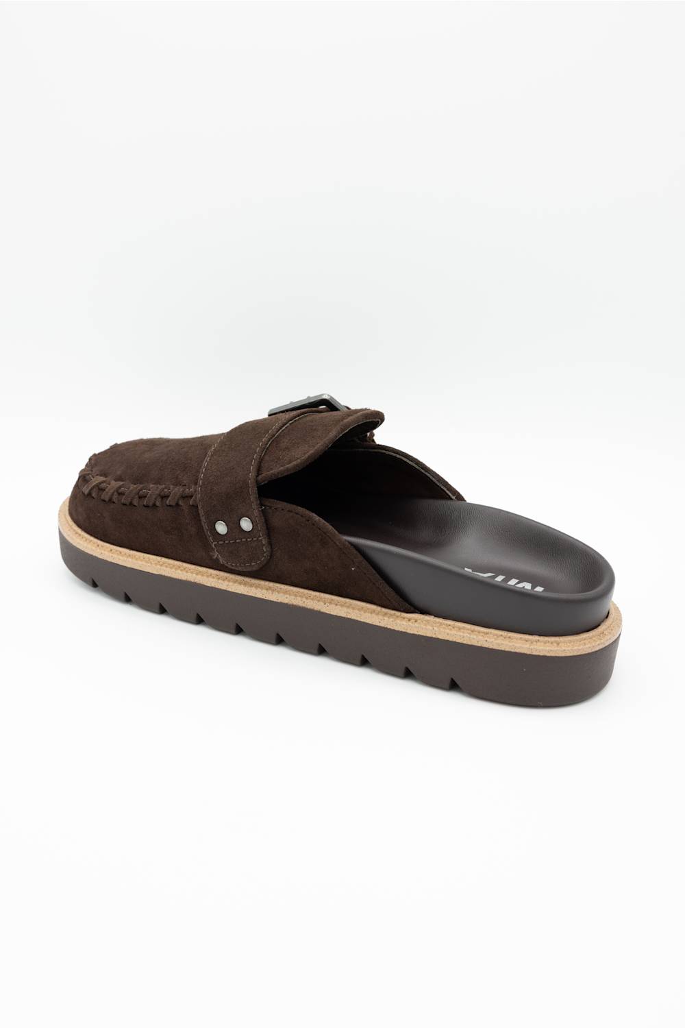 A dark brown suede mule slipper with a braided strap detail and a thick black sole, shown from a three-quarters angle on a white background.
