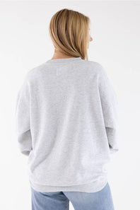 A woman viewed from behind wearing an oversized light gray heather crewneck sweatshirt and light blue jeans against a plain white background.