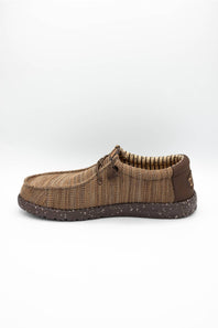 A single brown woven slip-on shoe with a textured knit upper, matching laces, and a speckled dark brown sole, shown against a plain light gray background.