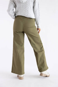 A person shown from the back wearing olive green wide-leg cargo pants, a light gray cable-knit sweater, and beige platform shoes against a plain white studio background.