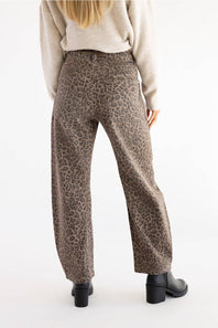 back view of woman modeling cheetah print jeans with black boots and tan sweater 