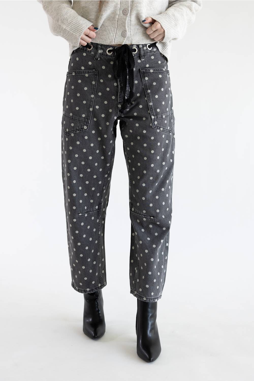 Front view of Aaron & Amber Drawstring Polka Dot Barrel Jeans in black showing full-length barrel silhouette, eyelet drawstring tie, and black heeled boots.