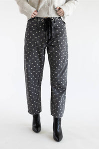 Front view of Aaron & Amber Drawstring Polka Dot Barrel Jeans in black showing full-length barrel silhouette, eyelet drawstring tie, and black heeled boots.