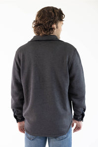 A man viewed from behind wearing a dark charcoal gray long-sleeve fleece pullover shirt and blue jeans against a plain white background.