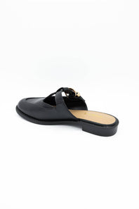 A black leather mule loafer with a decorative gold-tone metal hardware detail across the strap, shown from a side profile on a white background.