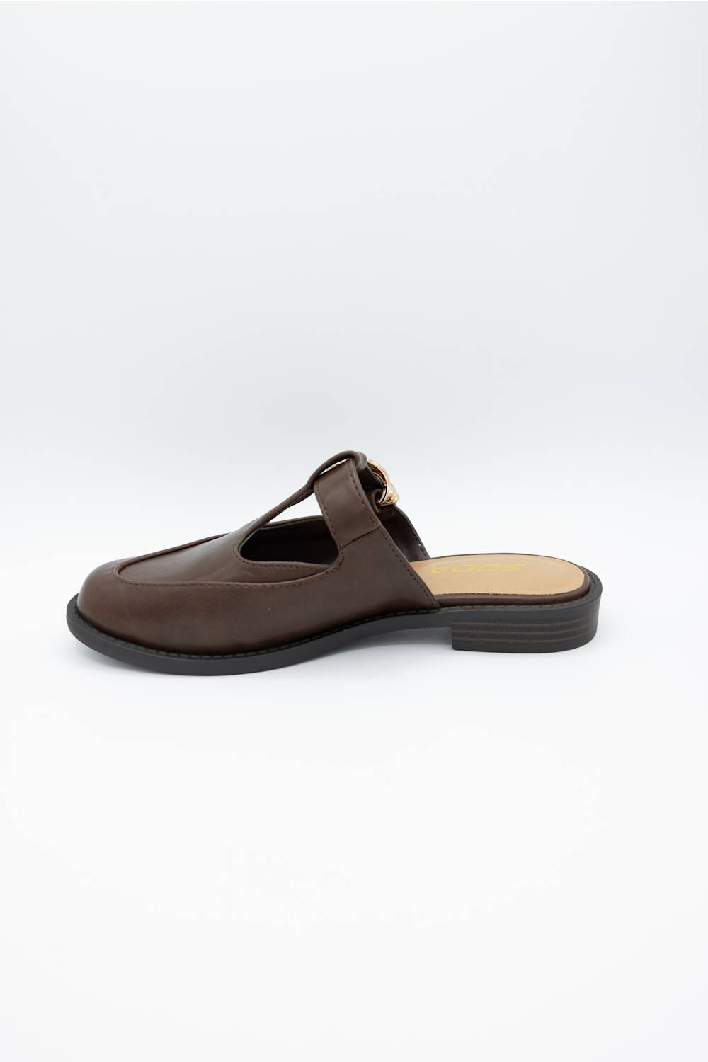 A dark brown leather mule sandal with a T-strap and a small gold-tone buckle detail, shown from a side profile on a light gray background.