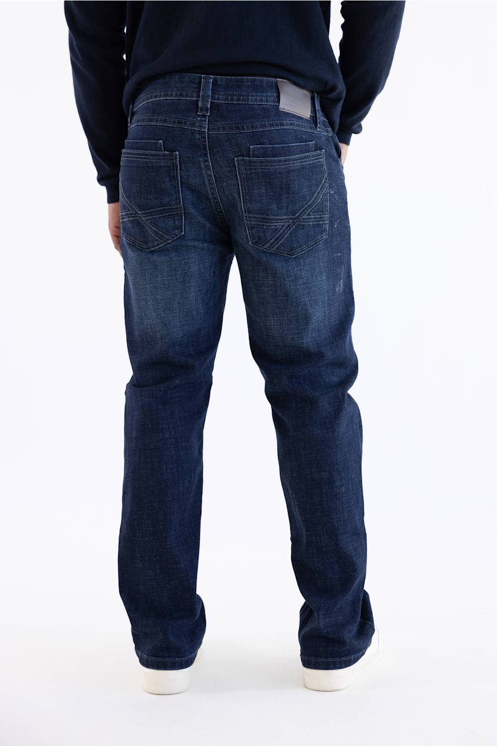 Rear view of a person wearing dark blue denim jeans and a dark navy long-sleeve top against a plain white background.