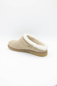 A single beige suede slip-on clog shoe with a white shearling-style lining and a tan sole, shown from a side profile on a white background.