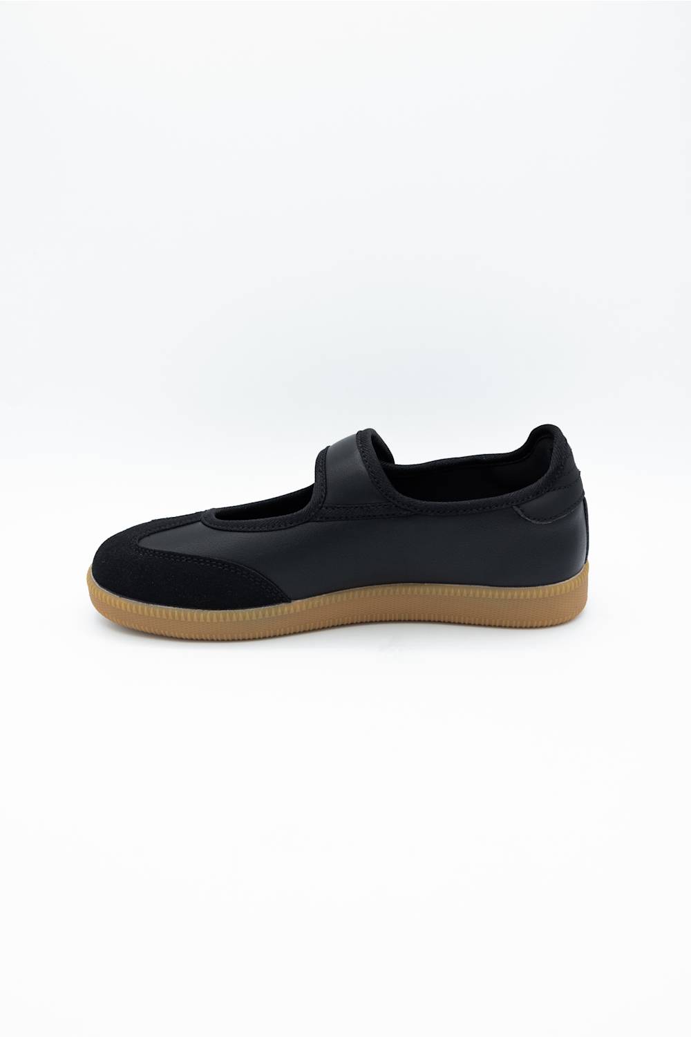 A black slip-on shoe with a tan gum sole, shown from a side profile view against a plain white background.