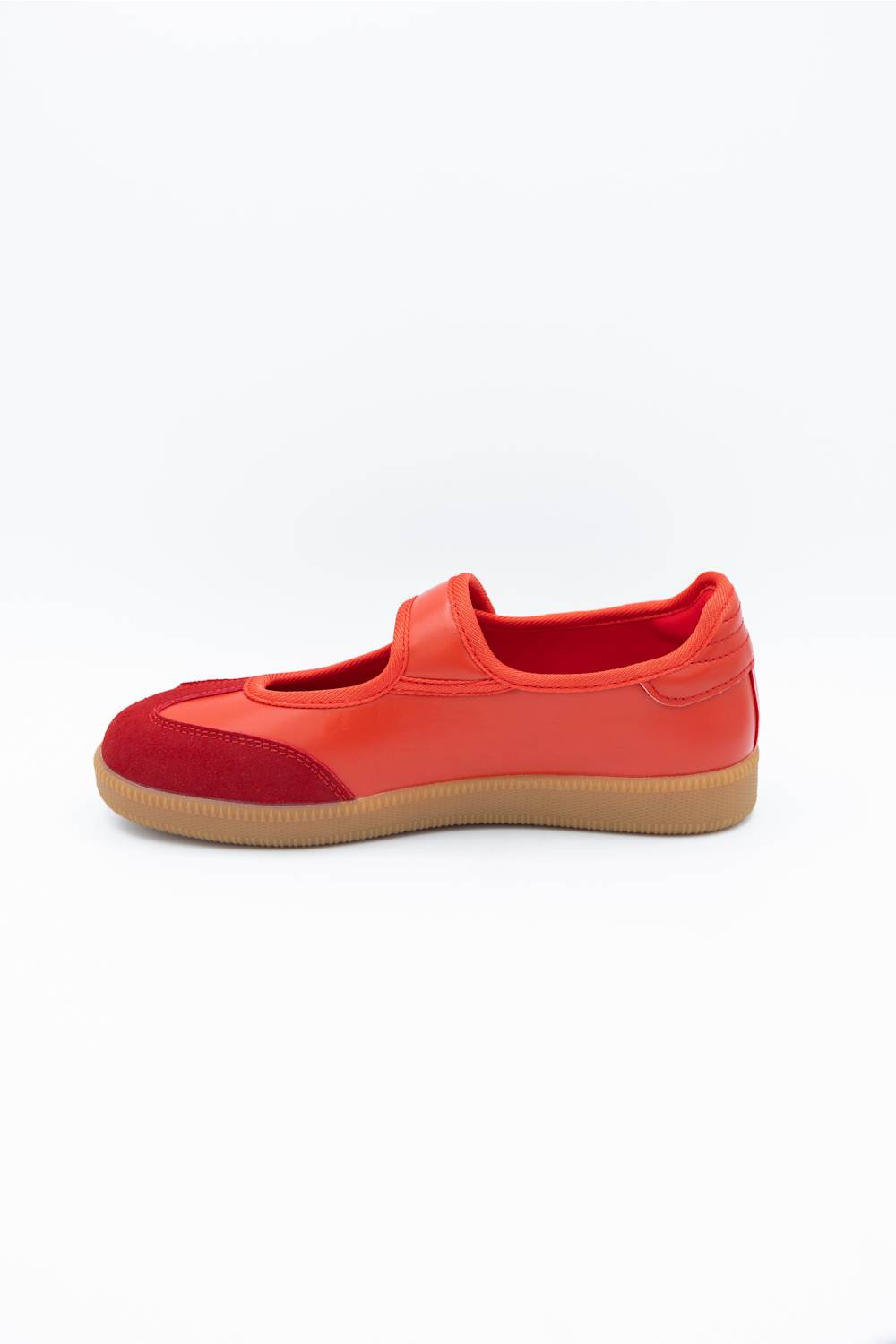 A red slip-on shoe with a suede toe cap and a gum rubber sole, shown from a side profile on a white background.