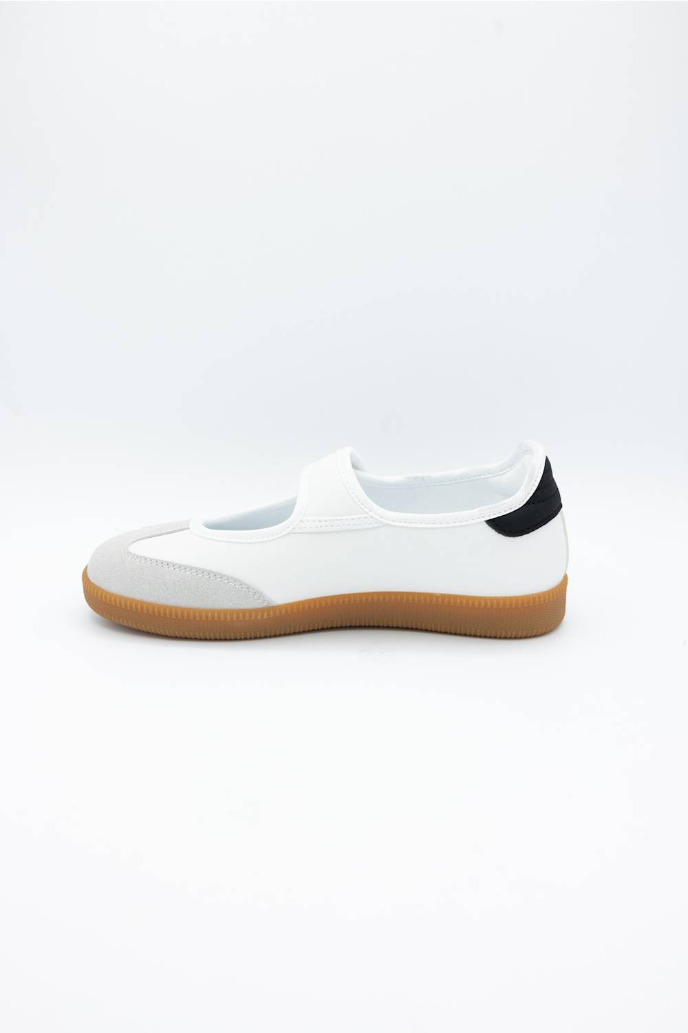 A white slip-on shoe with a gum brown sole and a small black heel accent, shown from a side profile on a white background.