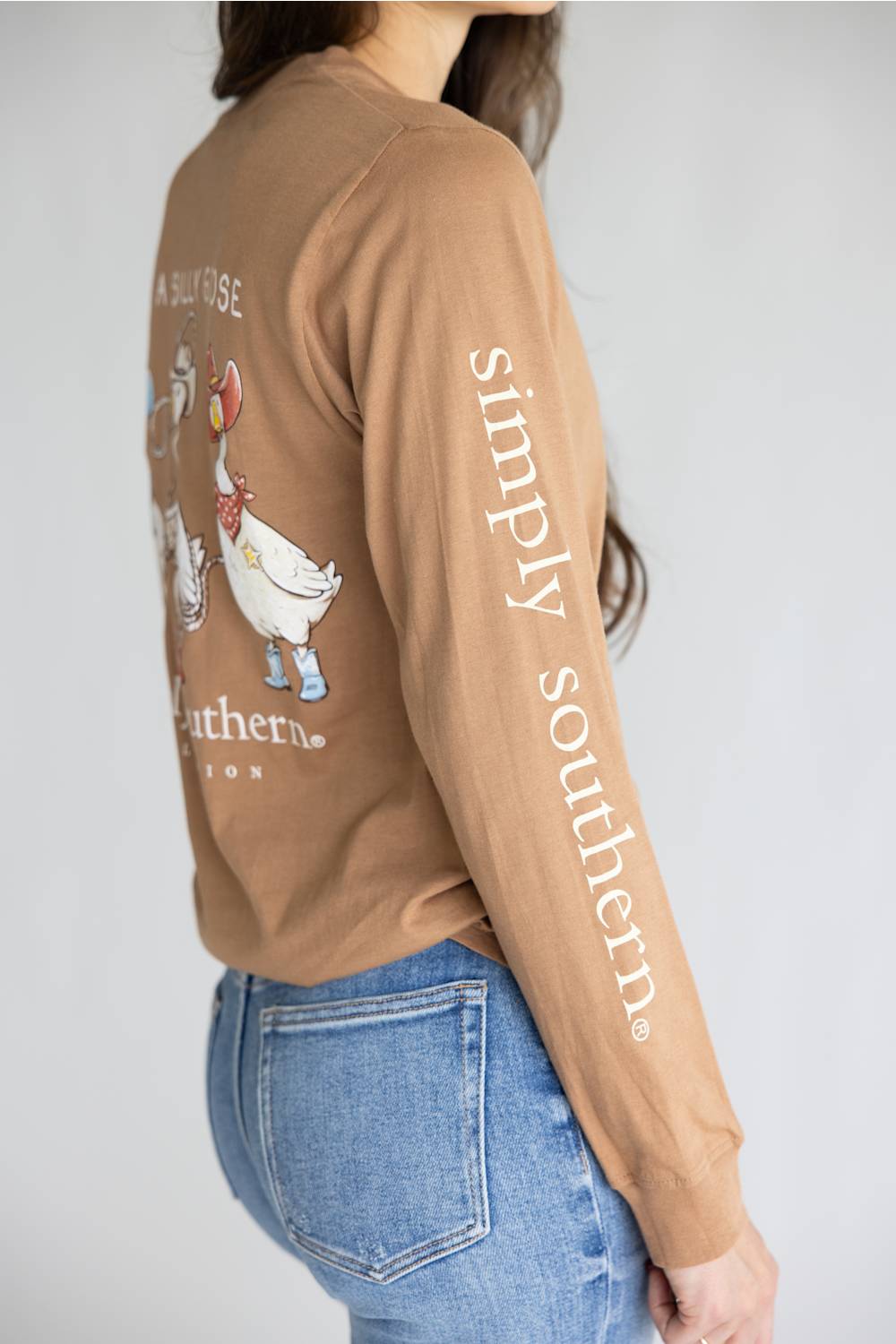 A brown long-sleeve t-shirt with a graphic of three western-style geese on the back, featuring the text 'JUST A SILLY GOOSE' and 'simply southern.' on the back, and 'simply southern.