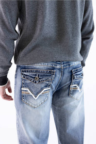 Rear view of a male model wearing True Luck Mac Loose Straight medium-wash jeans with detailed embroidered flap back pockets and whiskering, paired with a grey long-sleeve sweater against a plain white background.