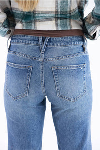 Rear view of a person wearing light blue denim jeans and a green and white plaid shirt against a plain white background.