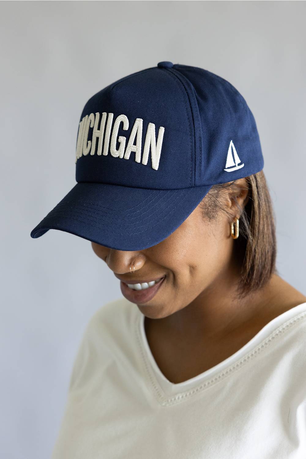 Michigan 3D Stitch Dad Hat in Navy; Woman wearing a navy blue cap with 'Michigan' text on a gray background