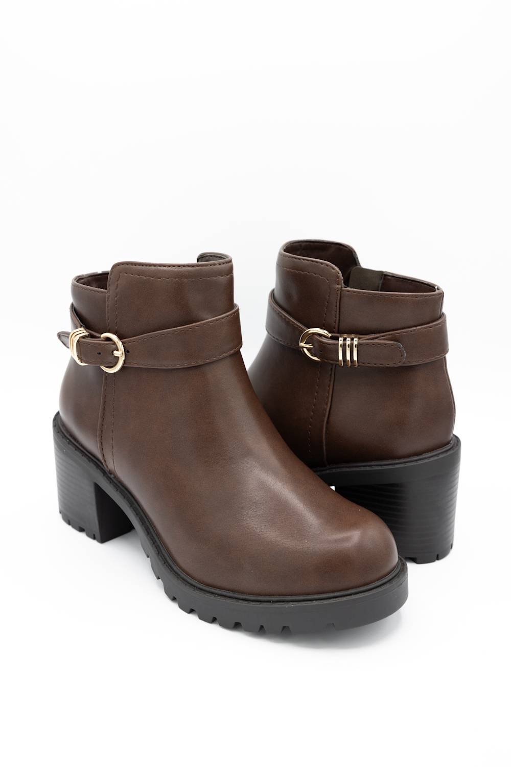 A pair of dark brown faux-leather ankle boots with a chunky black block heel, a matching strap across the ankle with a gold-tone buckle, and a textured lug sole, shown on a white background.