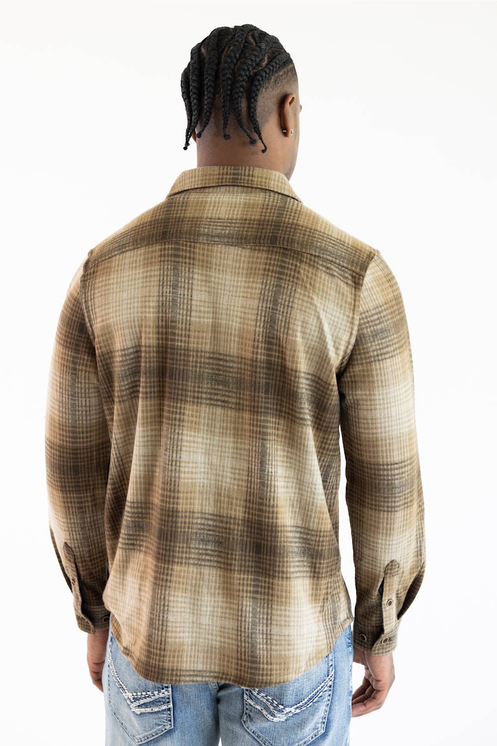 A man viewed from behind wearing a brown and beige plaid button-down shirt and blue jeans against a plain white background.