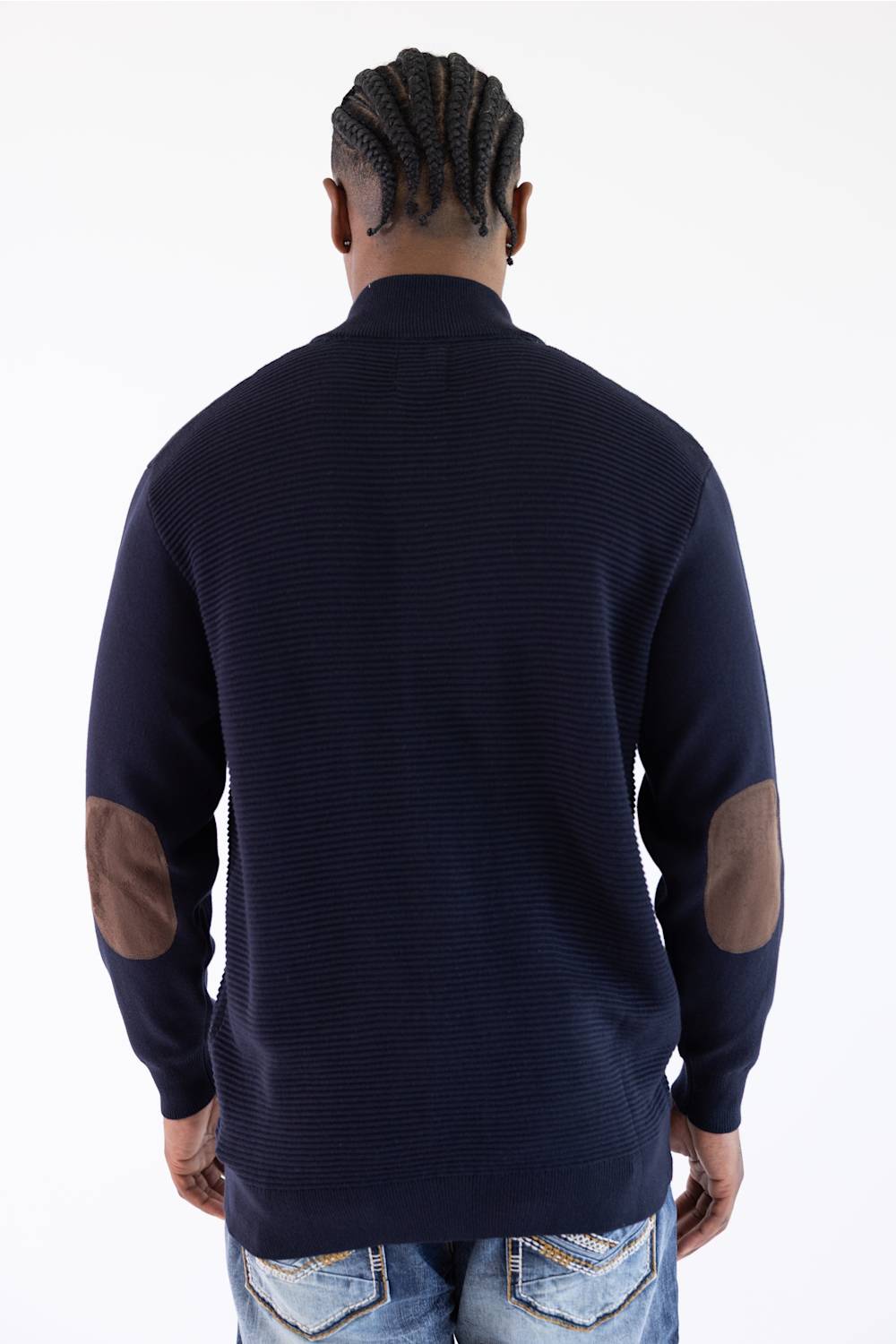 Man shown from the back wearing a navy mock neck jacket with brown elbow patches standing against a white background