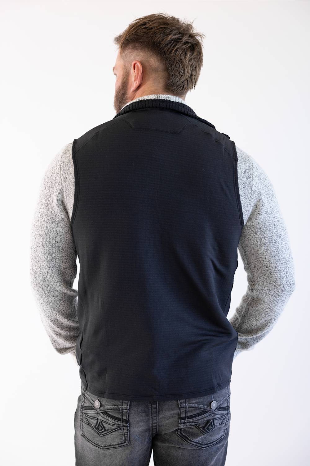 Back view of Patagonia Men's R1 Vest in Black styled over a heather grey sweater and dark jeans