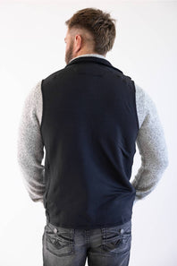 Back view of Patagonia Men's R1 Vest in Black styled over a heather grey sweater and dark jeans