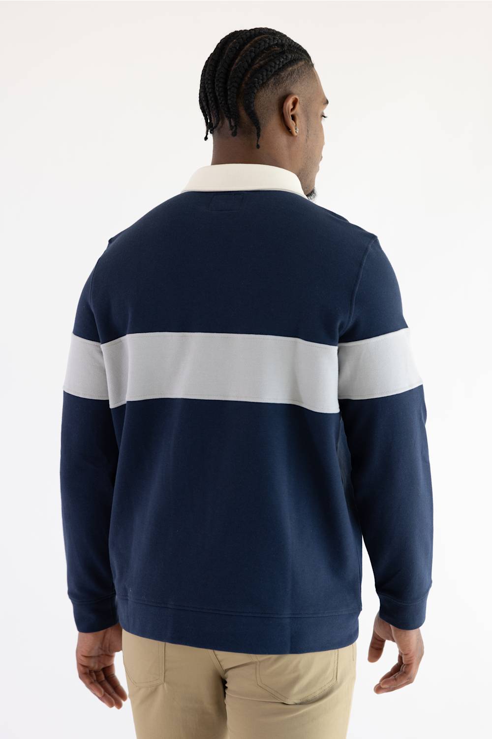 back view of a man wearing a navy and grey polo shirt with long sleeves and khakis