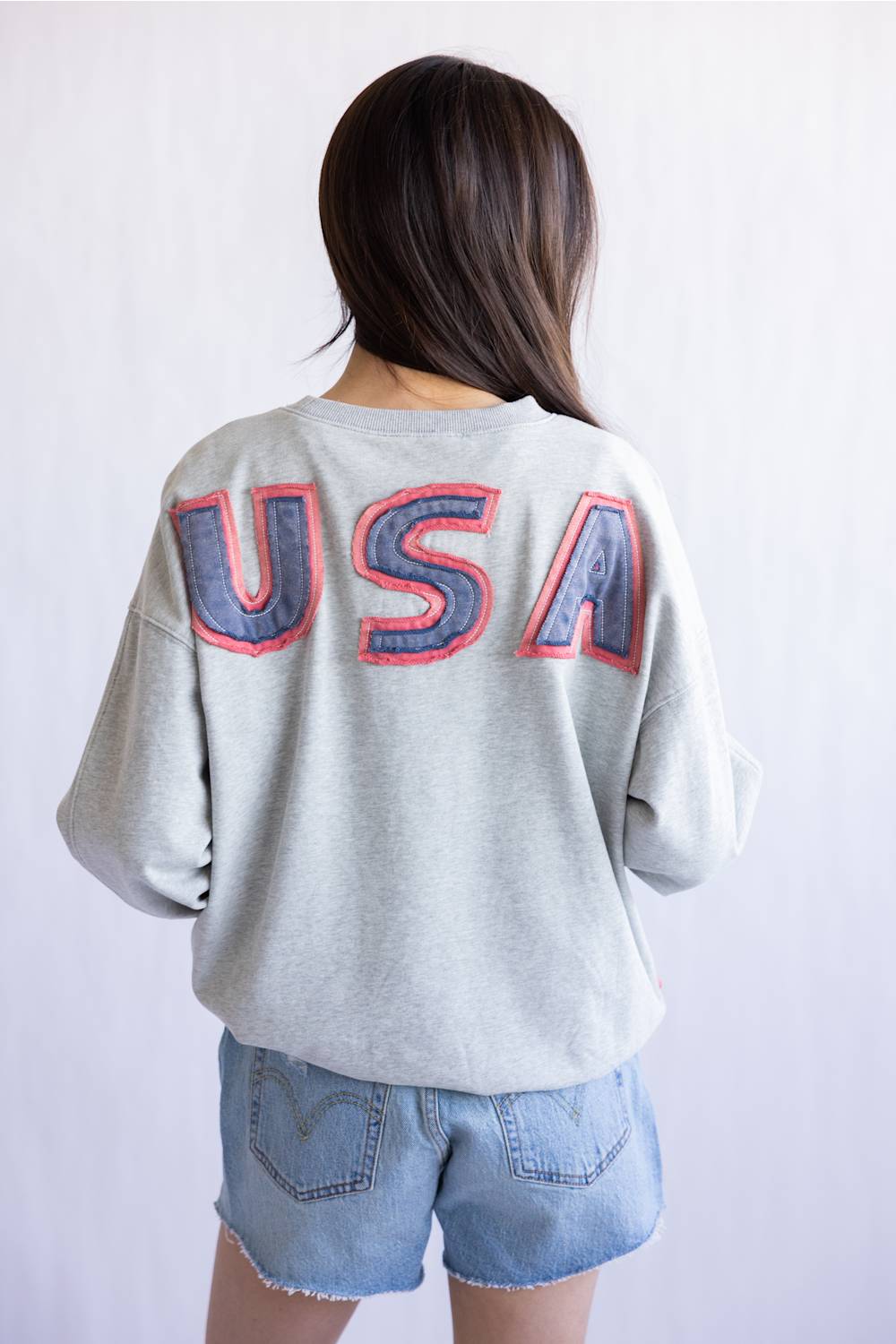 Flag USA Sweatshirt for Women in Grey; Person wearing a gray sweatshirt with 'USA' printed on the back against a white background