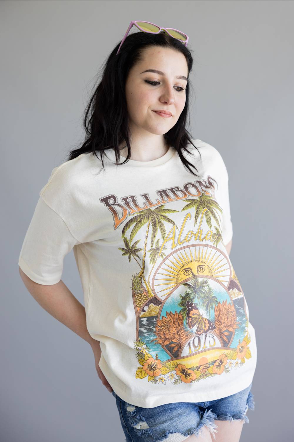 Person wearing a graphic t-shirt with palm trees and text on a plain background