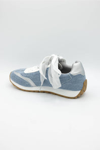 A light blue and white low-top sneaker with white laces and a brown gum sole, shown from a side angle on a light gray background.