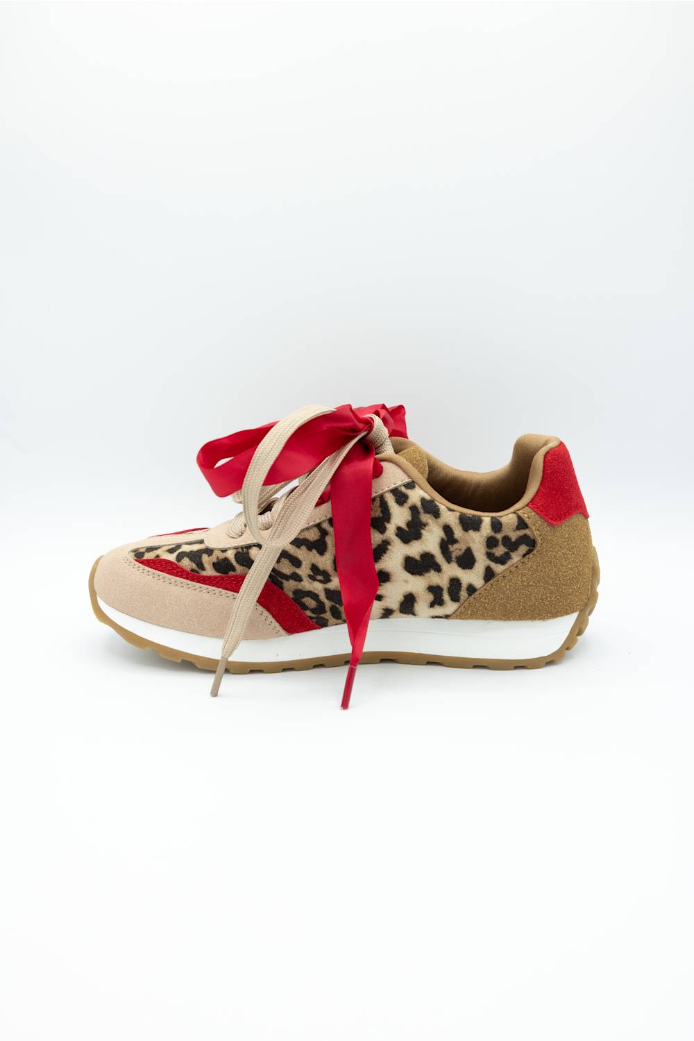 A low-top sneaker featuring a leopard print pattern on the side, beige suede-like panels, a red heel tab, and a red ribbon tied around the laces, shown against a plain white background.