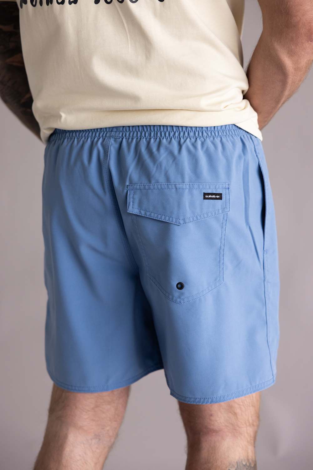 Back view of a person wearing blue shorts with a visible brand logo on a plain background. The shorts are the Quiksilver Saltwater Volley 17" Swim Trunks for Men in Riviera